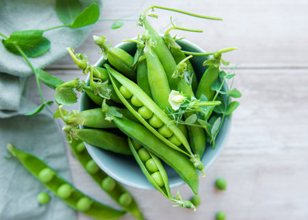 Bowl with young fresh juicy pods of green peas on a wooden background. Healthy organic food.の写真素材