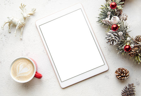 Christmas decorations and tablet on white concrete background. Christmas and New Year theme. Flat...