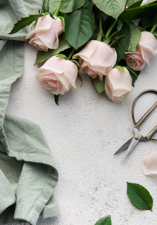 Top view of a bouquet of pink roses, scissors and fabric on a grey concrete background. Florist work place. Accessories for making bouquets and floral compositions.の写真素材