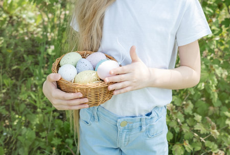 Cute little child wearing bunny ears on Easter day. Girl holding basket with painted eggs.