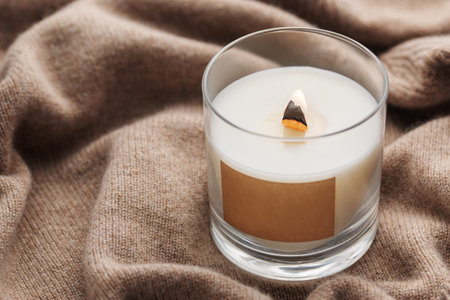 A candle burns on the background of a knitted sweater. The concept of cozy winter or autumn.の写真素材