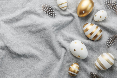 Easter eggs are painted with gold paint on a gray linen background. Concept of Easter holidays....