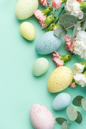 Easter colored eggs and a bouquet of white and pink carnations with eucalyptus branches on a soft green background. Festive background.の写真素材