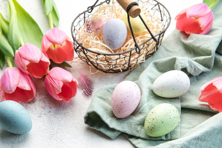 Basket with Easter eggs painted  pastel colors and pink tulips on a concrete background. Top view. Space for text.の写真素材