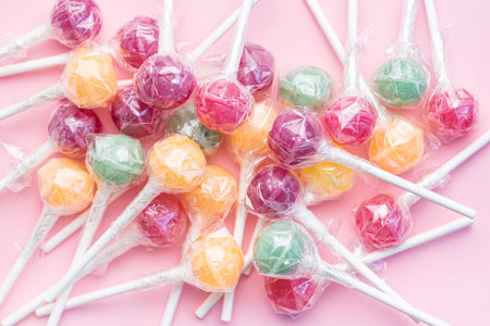 Colorful sweet lollipops over pink background.  Flat lay, top view