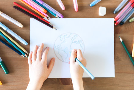 Child girl drawing with colorful pencils at home. Ecology concept, painting earth.の写真素材