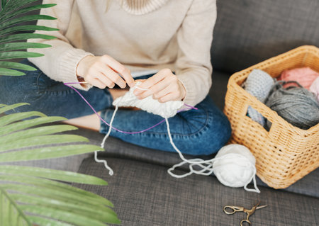 Young woman knitting warm scarf at home