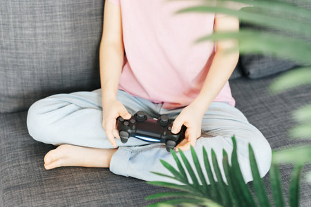 A little girl is playing with a game console at home.