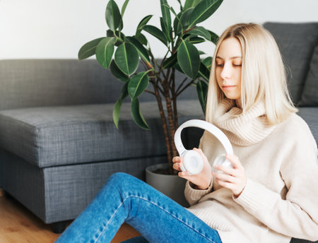 Young blonde woman in headphones listening to music and relaxing at home.の写真素材