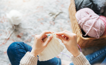Young woman knitting warm scarf at home