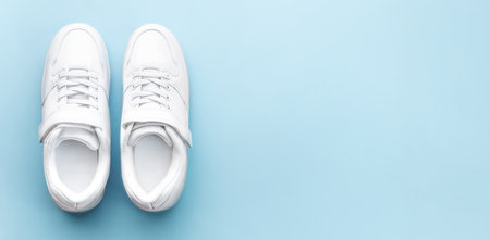 White children's sneakers on a blue background with copy space. Banner.の写真素材