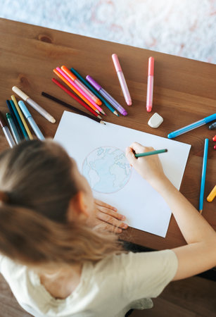 Child girl drawing with colorful pencils at home. Ecology concept, painting earth.の写真素材