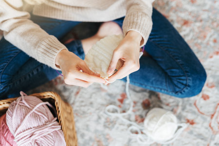 Young woman knitting warm scarf at homeの写真素材