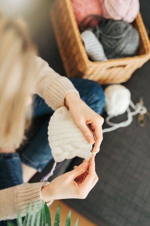 Young woman knitting warm scarf at homeの写真素材