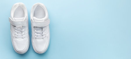 White children's sneakers on a blue background with copy space. Banner.の写真素材