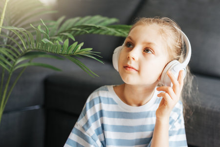 Cute little girl listening to music in headphones  at home.の写真素材