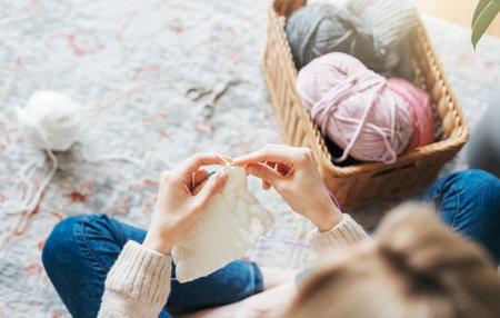 Young woman knitting warm scarf at homeの写真素材