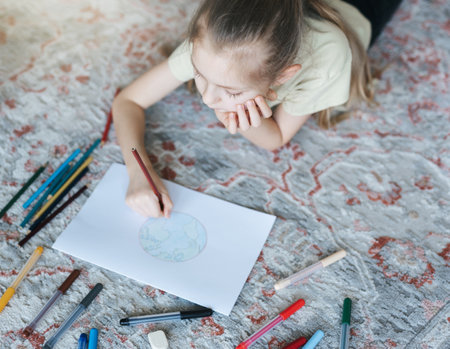 Child girl drawing with colorful pencils at home. Ecology concept, painting earth.の写真素材