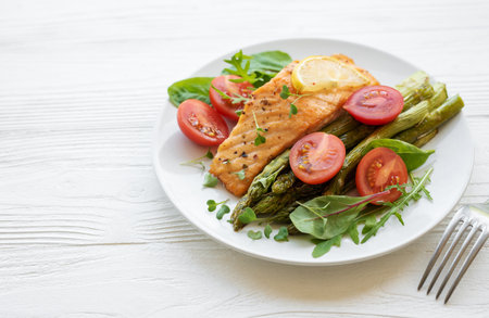 Baked Delicious salmon, green asparagus with vegetables on plateの写真素材
