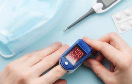 Pulse oximeter measuring oxygen saturation in blood and heart rate.  Pulse oximeter on the patient's...