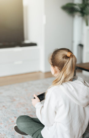 A little girl is playing with a game console at home.の写真素材