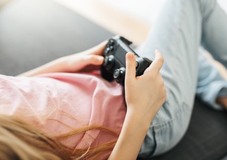 A little girl is playing with a game console at home.
