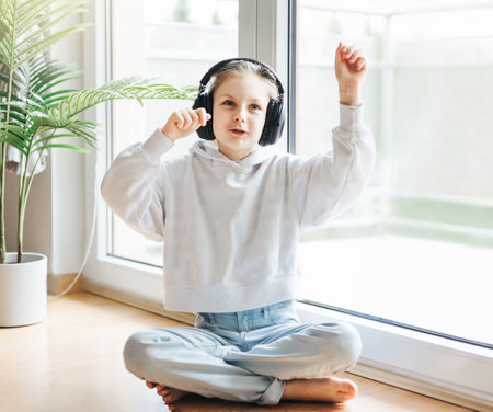 Cute little girl listening to music in headphones  at home.の写真素材