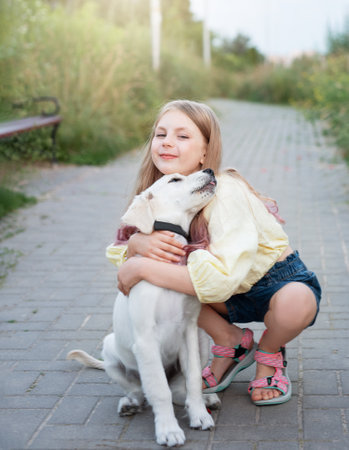 Puppy labrador retriever and little girl. Little girl playing with golden retrieverの写真素材