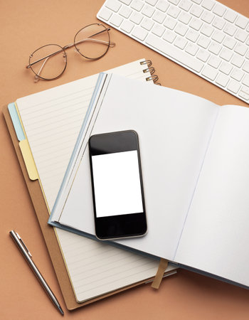 Top view  of office  supplies, smartphone with blank mockup screen, over notebooks,  pens, glassesの写真素材