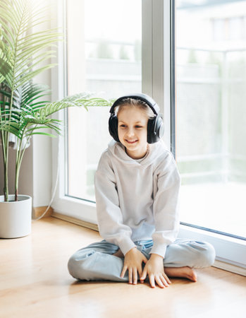 Cute little girl listening to music in headphones  at home.の写真素材
