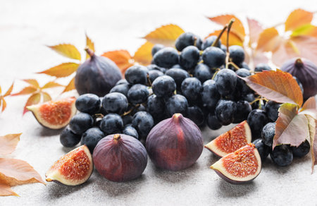 Fresh ripe figs and dark grapes with autumn leavesの写真素材