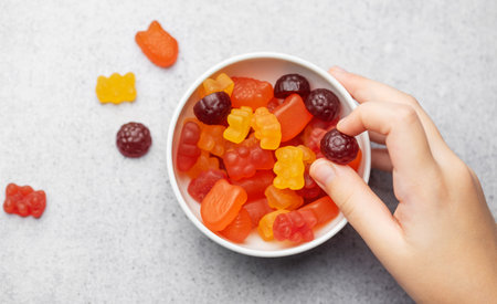 Chewable gummy bears vitamins and supplements.  A girl holds a gummy bear vitamines in her hands.の写真素材