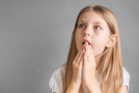 Portrait of a surprised little girl, girl with long blonde hair in white t-shirtの写真素材