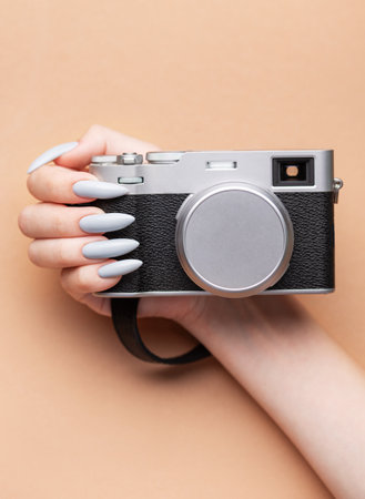 Close up of woman's hand with grey nail polish holding cameraの写真素材