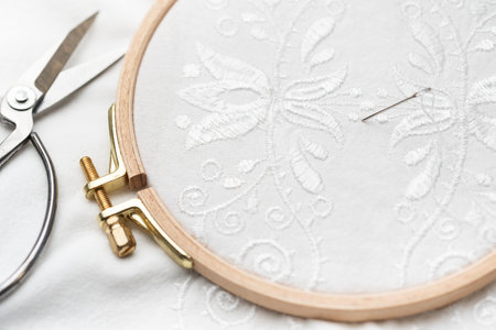 The process of hand embroidering a shirt with white threads on white fabric.