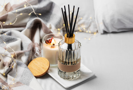 Cozy home atmosphere. Home liquid fragrance in glass bottle and scented candle on  tray.
