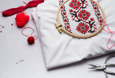 Embroidery with colored threads and various sewing accessories on the tableの写真素材