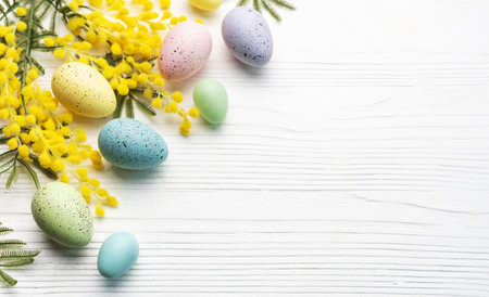 Colorful easter eggs  and mimosa flowers on wooden table. Top view with copy spaceの写真素材