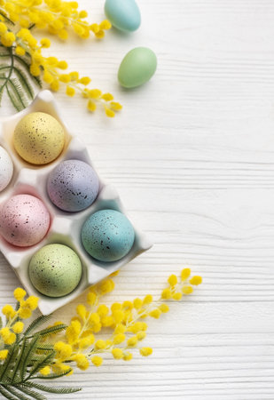 Colorful easter eggs  and mimosa flowers on wooden table. Top view with copy spaceの写真素材