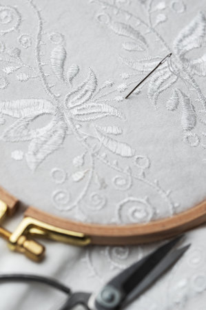 The process of hand embroidering a shirt with white threads on white fabric.の写真素材