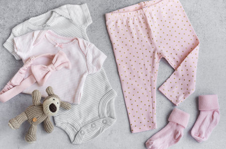 Set of baby bodysuits, pants, socks and knitted toy on grey background. Fashion baby clothes and accessories. Flat lay, top viewの写真素材