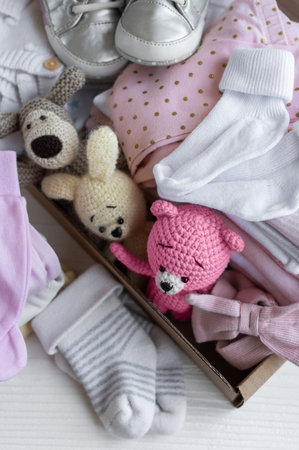 Baby clothes, knitted toys, socks and shoes in box. Second hand apparel idea, donation, charity conceptの写真素材