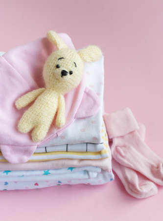 Stack of Baby bodysuits. Baby knitted toy of bunny next to a stack rompers for kidsの写真素材
