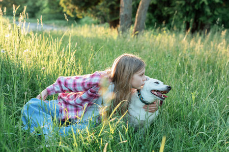 A child with a dog in nature, girl playing with a dog on green grassの写真素材