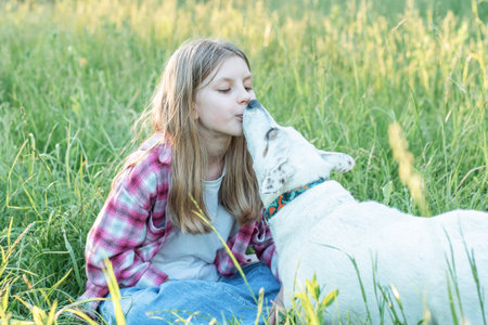 A child with a dog in nature, girl playing with a dog on green grass