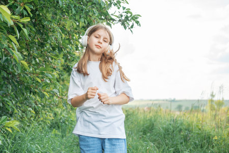 A child  with headphones listening to music and dancing in the park.の写真素材