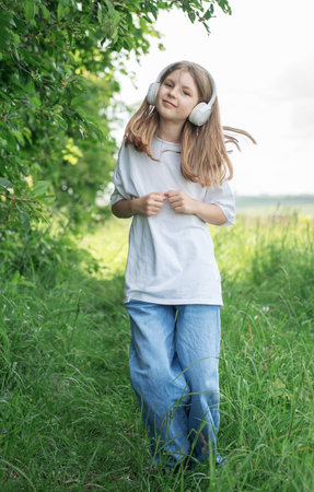 A child  with headphones listening to music and dancing in the park.の写真素材