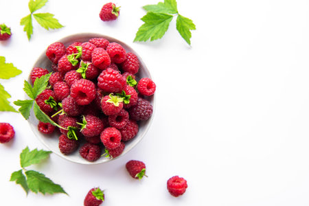 Fresh organic ripe raspberry with leaves on a white background