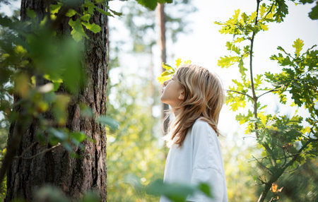 A teenage girl hugs a tree in the forest. Hugging and touching trees to reduce stress and connect...