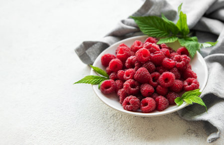 Fresh organic ripe raspberry with leaves on a concrete  background